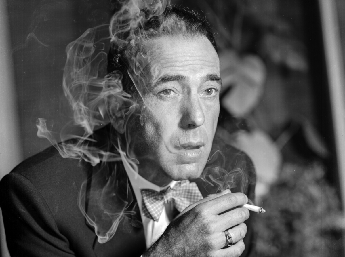 Headshot of actor Humphrey Bogart, wearing a bow tie and smoking a cigarette