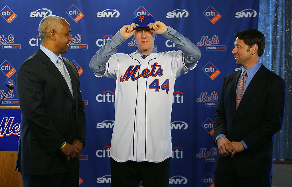 General Manager Omar Minaya watches Jason Bay and put on a New York Mets hat as Mets COO Jeff Wilpon looks on during a press conference to announce Bay's signing to the New York Mets on January 5, 2010 at Citi Field in the Flushing neighborhood of the Queens borough of New York City-95590271