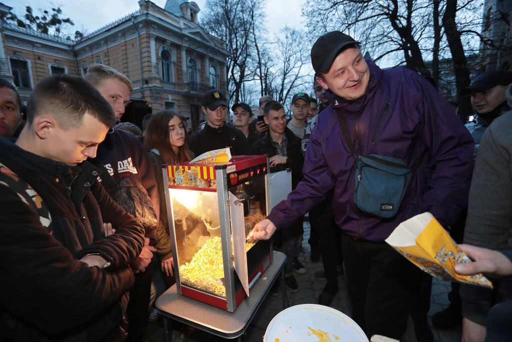 Outside, people surround a mini popcorn maker.