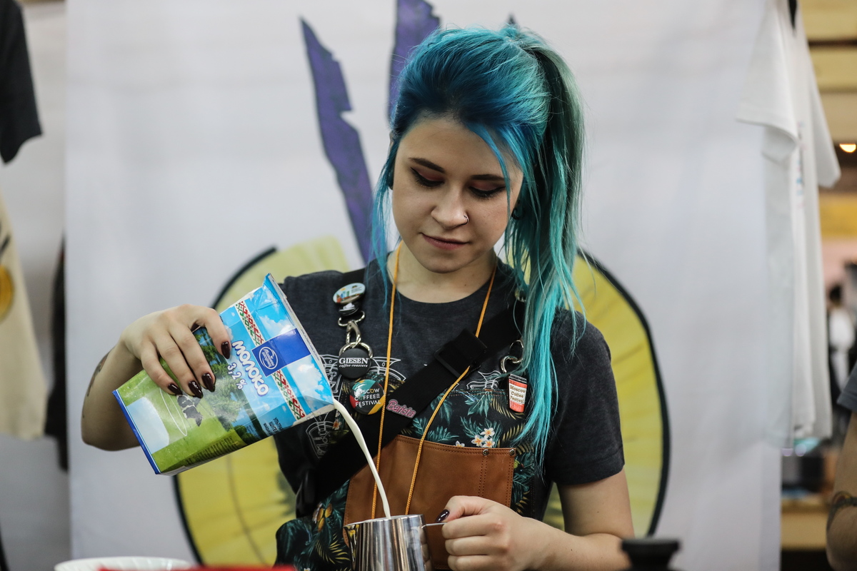Woman pours coffee cream while making coffee for a coffee cupping session during the Moscow Coffee Festival