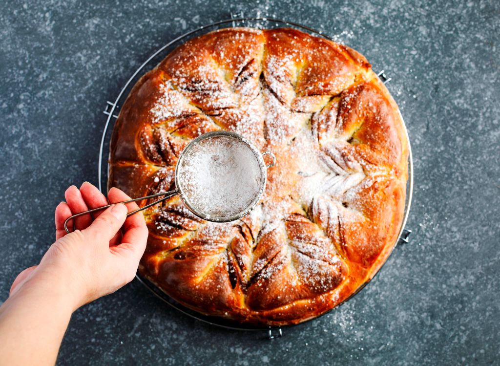 Powdered sugar is dusted over a large brioche.