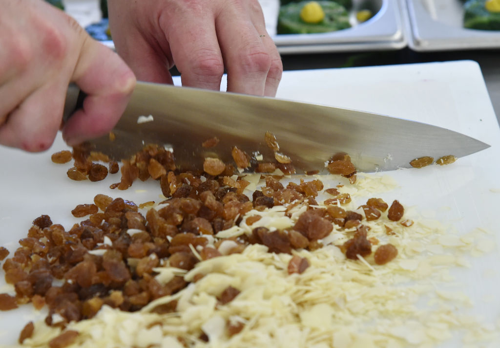 A chef is pictured taking a large knife to raisins and almonds.