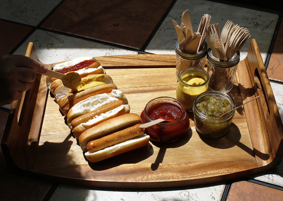 The author spreads hot mustard on a hot dogs along with homemade ketchup and zucchini-and-green pepper relish.