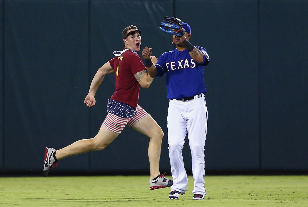 A fan runs across the field past Leonys Martin #2 of the Texas Rangers in the top of the eighth inning at Globe Life Park in Arlington on July 11, 2015 in Arlington, Texas.