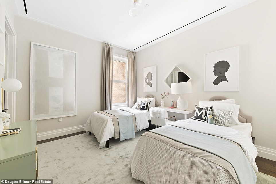 A Jack and Jill design features a desk between twin beds and a dresser along the oppisite wall.