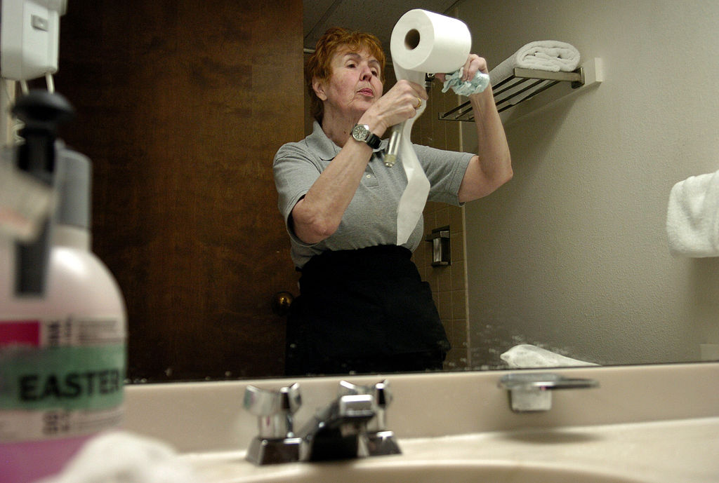 a woman putting toilet paper on a holder in a bathroom