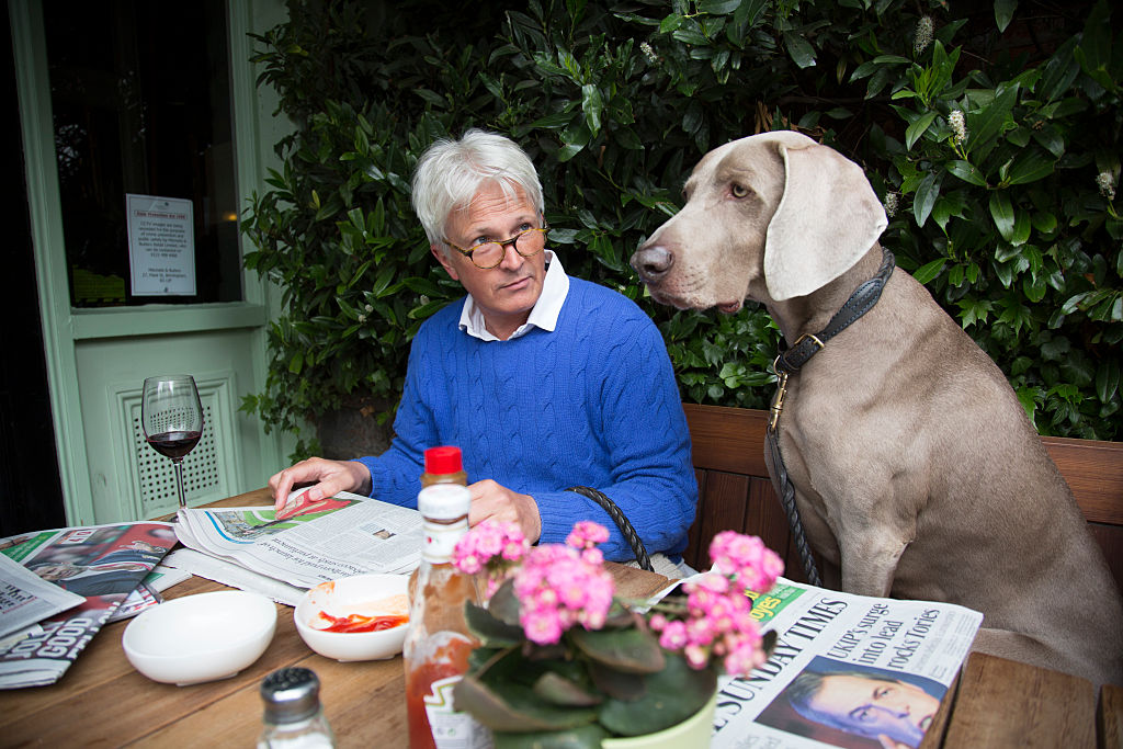 Man enjoying the Sunday newspapers with his Weimaraner dog Max 