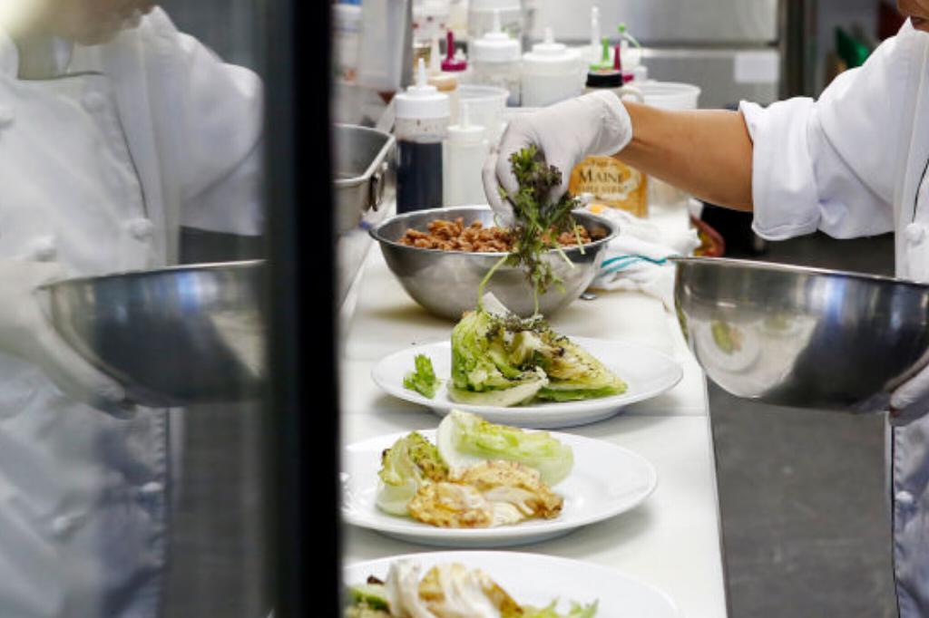 A Chef Prepares Salads A chef places toppings onto plates of salad