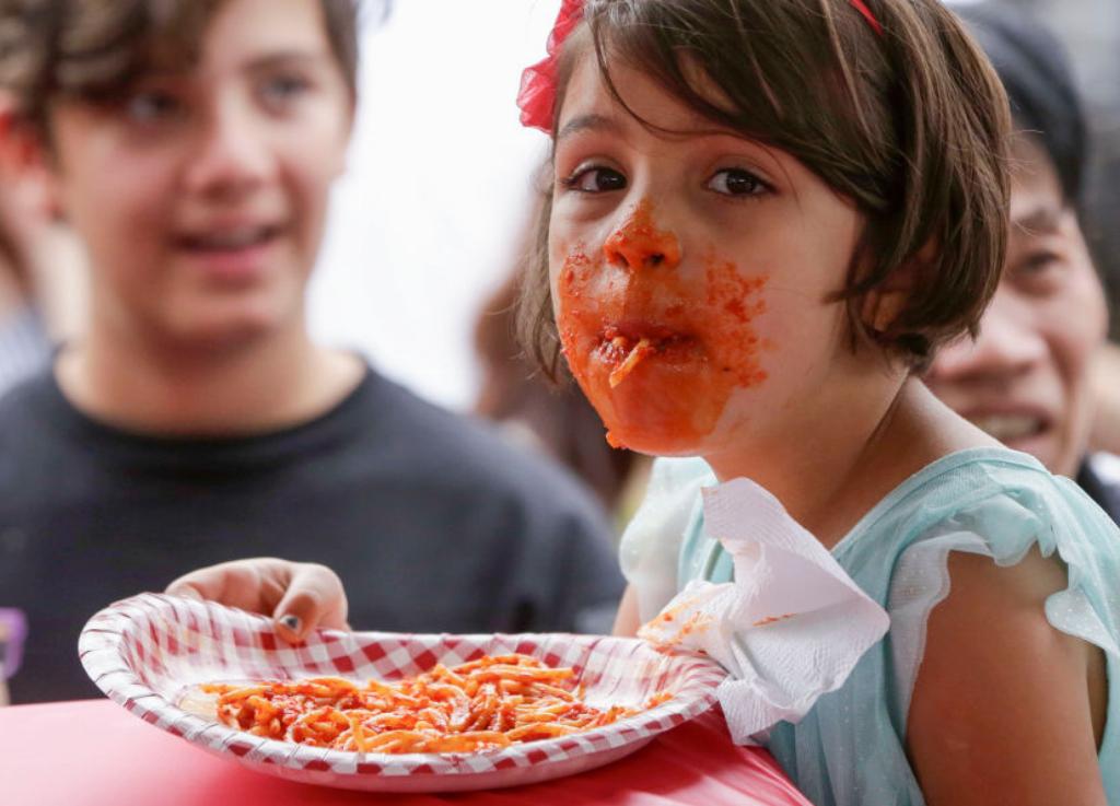 A Messy Girl Eats Pasta A young girl eating pasta wears sauce all over her mouth
