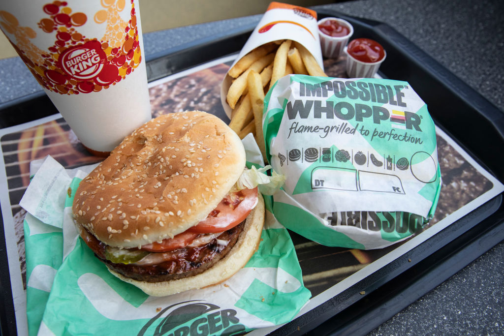 Two burgers, a carton of french fries, and a large soda sit on a tray for Burger King