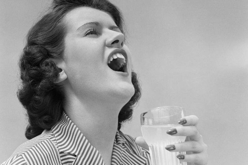 1940s WOMAN GARGLING HOLDING A GLASS