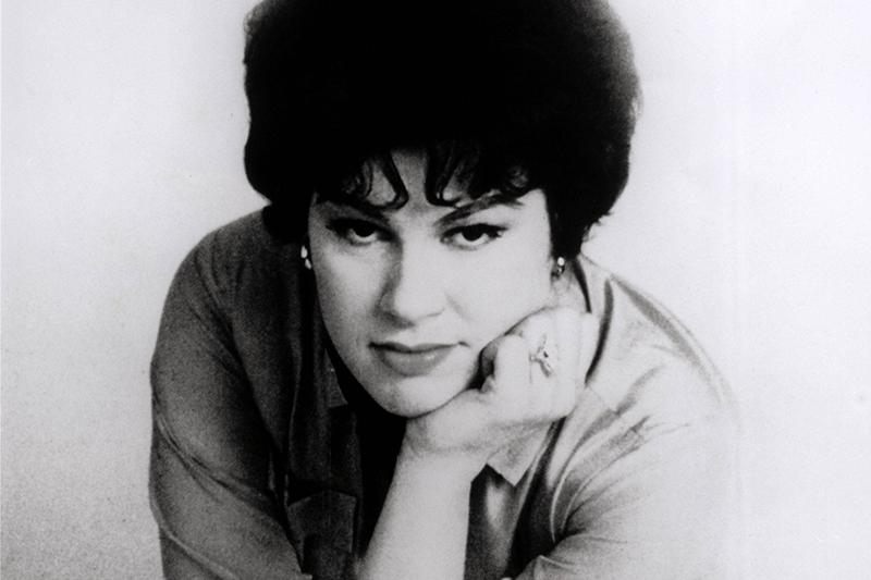 Patsy leans forward and looks up at the camera