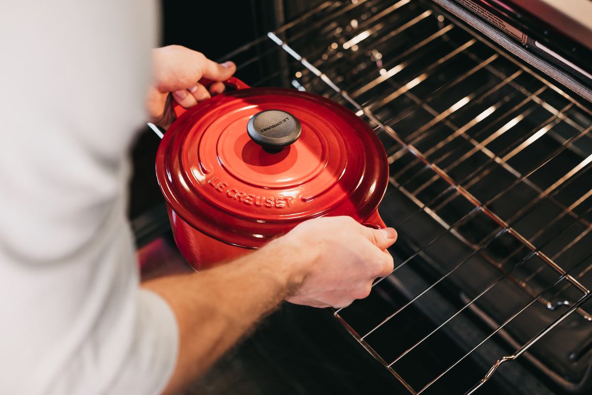 Man places red pot inside of oven