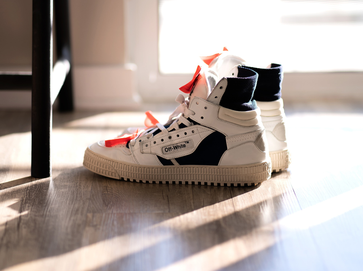 Off-white sneakers rest near a screen door
