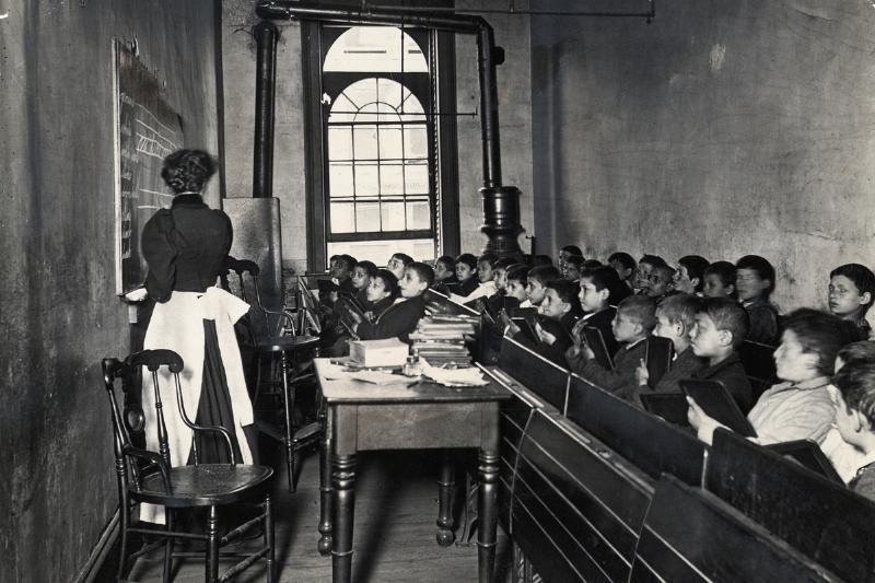 classroom 1886 - 515412336 A teacher demonstrates on the blackboard, as students watch attentively from crowded pews, circa 1886