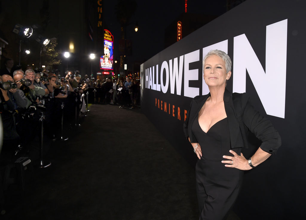 Jamie Lee Curtis poses in front of a giant Halloween poster.
