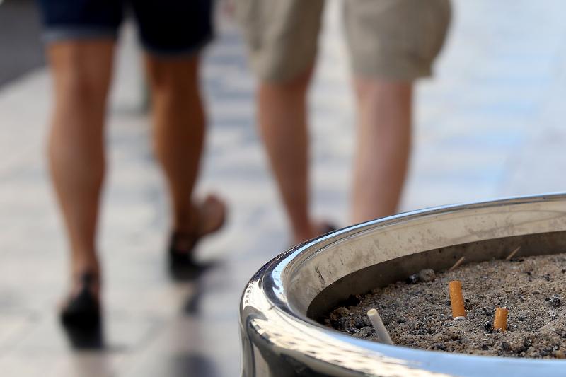 walking away - 1165966236 Two people walk away from an ashtray.