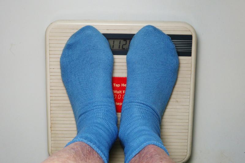 on a scale - 1178100931 A person stands on a scale to weigh himself.