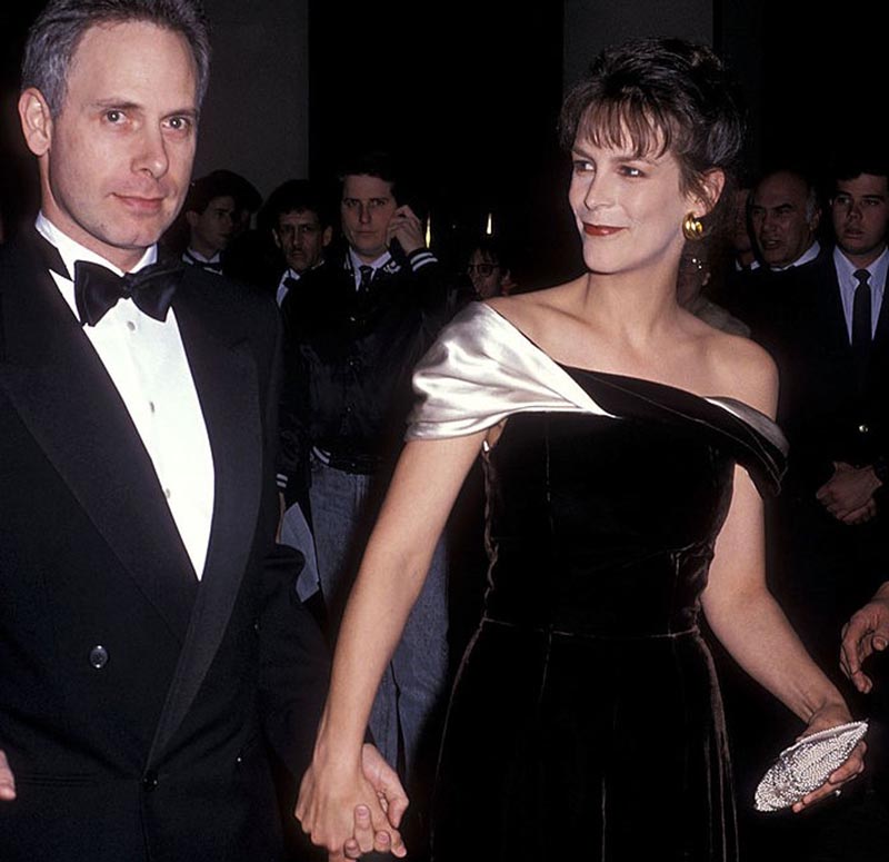 Jamie smiles at her husband while they walk through an event holding hands.