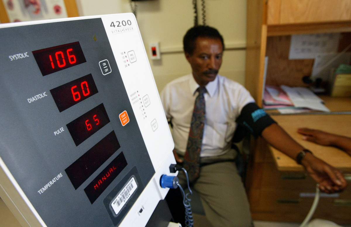 Negash Berhe has his blood pressure checked with a monitor.