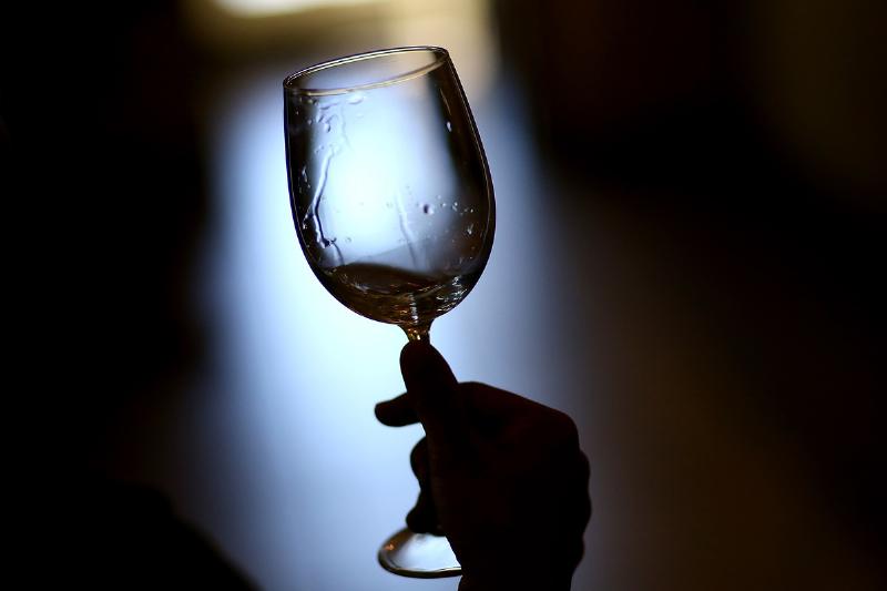 wet glass - 454224122 A visitor holds a glass while tasting at Madonna Estate.