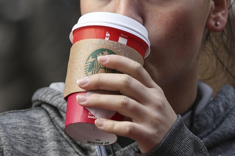drinking Starbucks - 496781352 A woman drinks Starbucks coffee in a red cup.