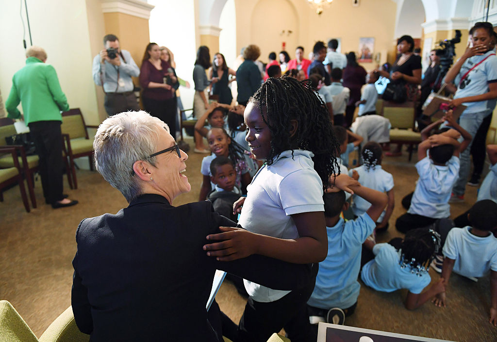 Jamie smiles at and embraces a young girl.