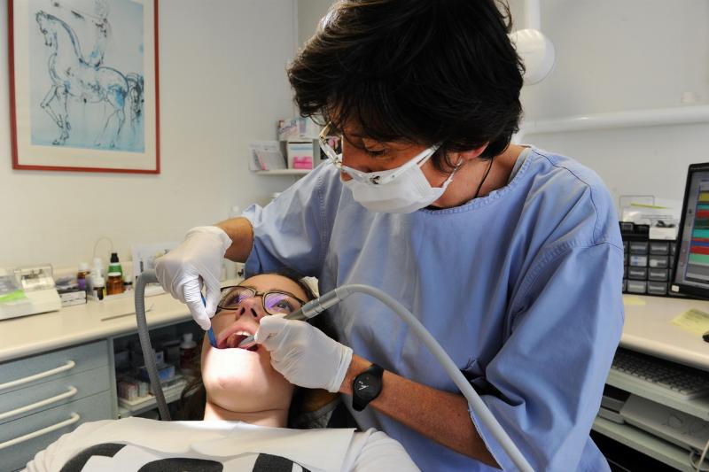 dentist - 668071946 A dentist cleans a patient's teeth.