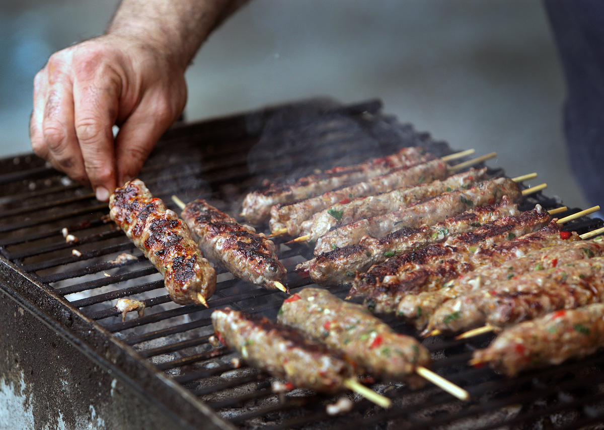 Man grills lamb kebabs.