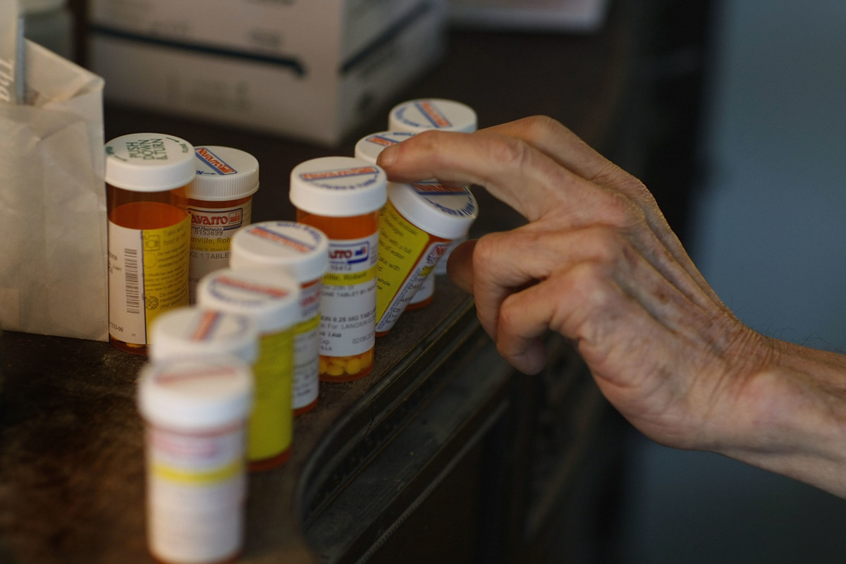 Robert Granville reaches for a medicine bottle as he takes his prescription pills.