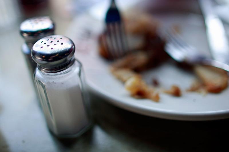 Salt and pepper shakers sit near a plate of food at a diner.