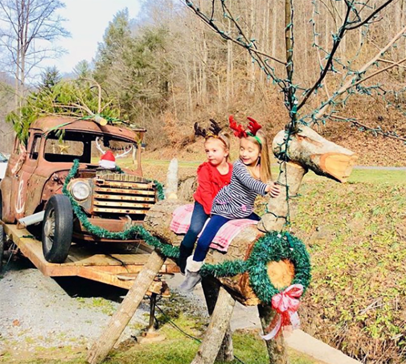 A wooden reindeer is fixed to a rusted, old car to look like Santa's sleigh.