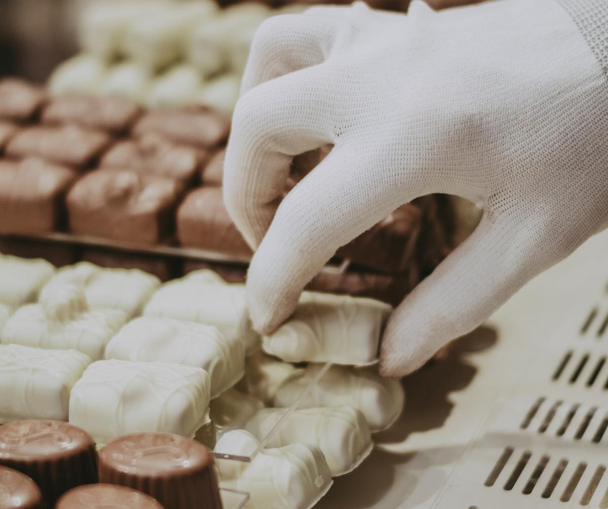choosing chocolate A person picks white chocolate from a stack of chocolates.