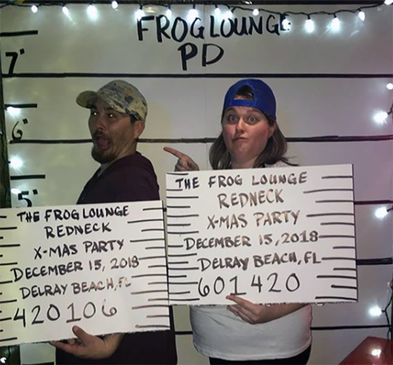 A man and woman make silly faces while posing for a fake mug shot.