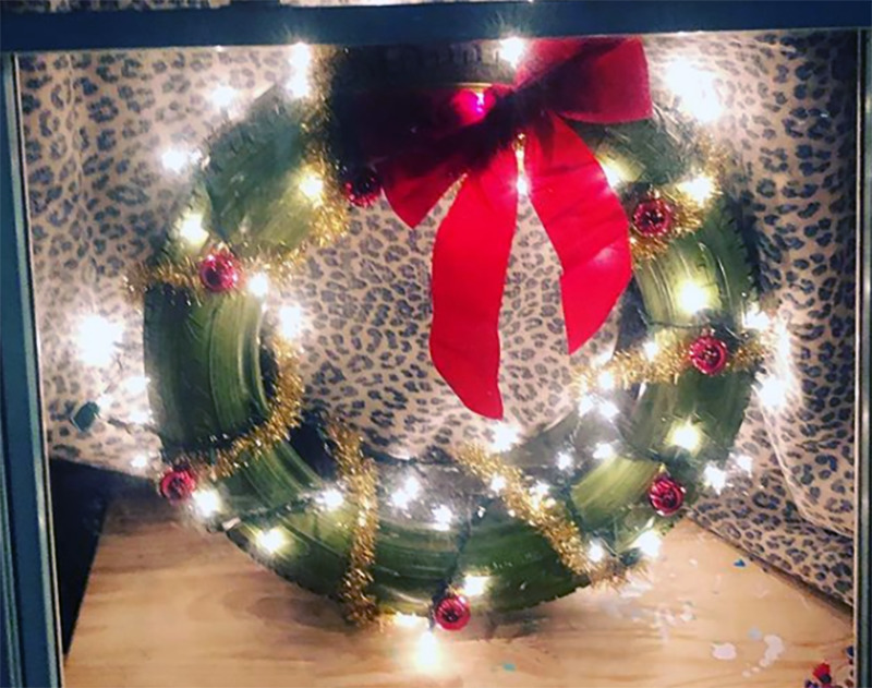 A tire is decorated as a wreath and placed in the window.