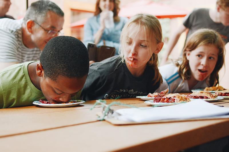 Kids participate in a pie eating contest.