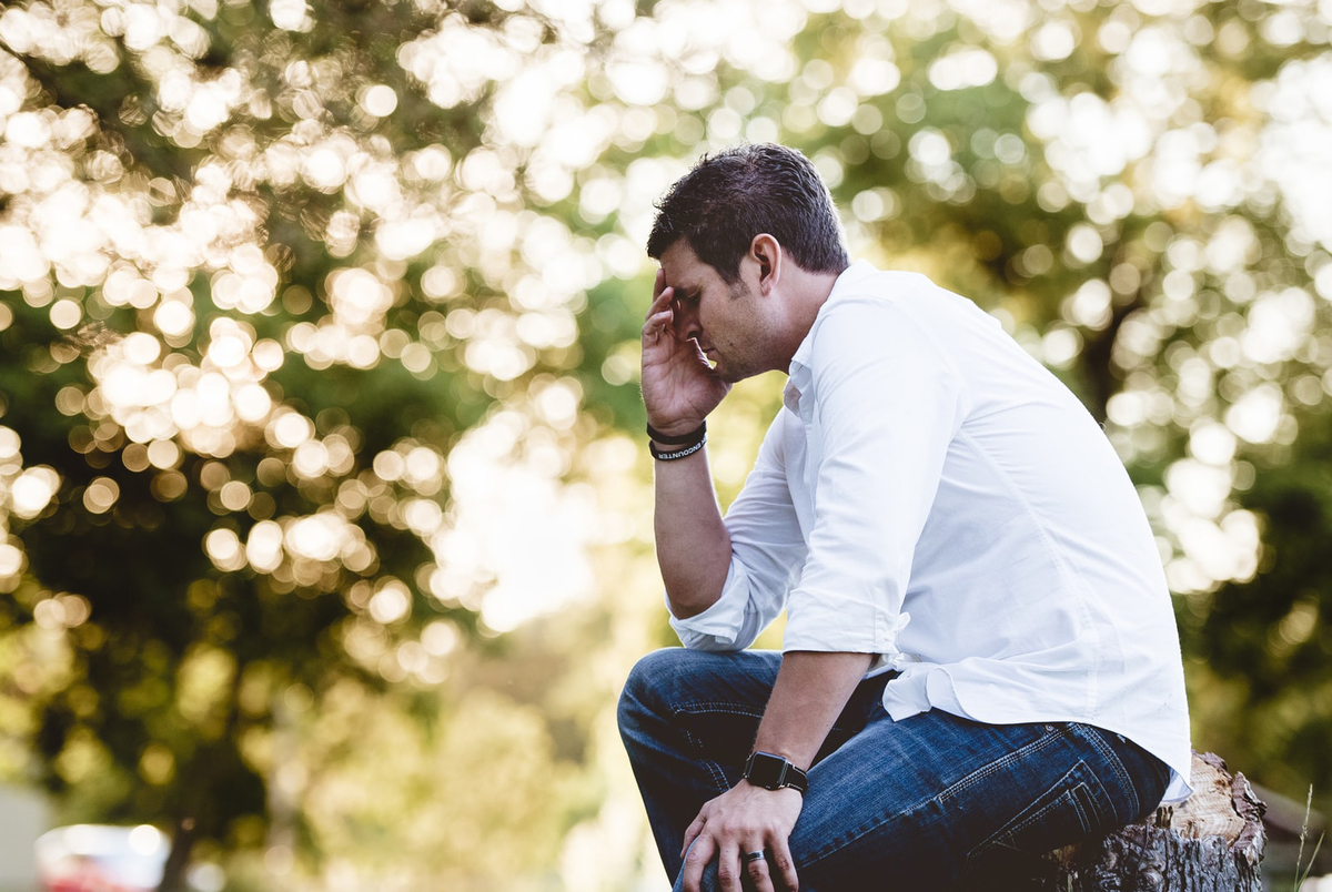 Stressed man contemplates his existence in front of bright lights.