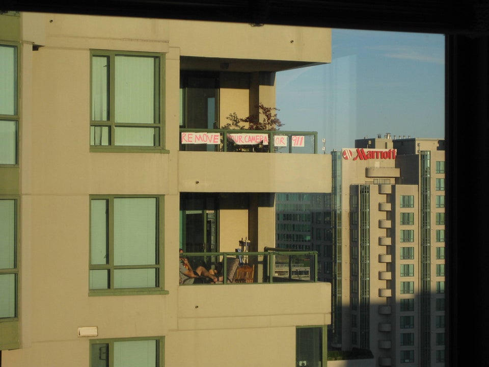A makeshift banner hanging on a high rise balcony reads 