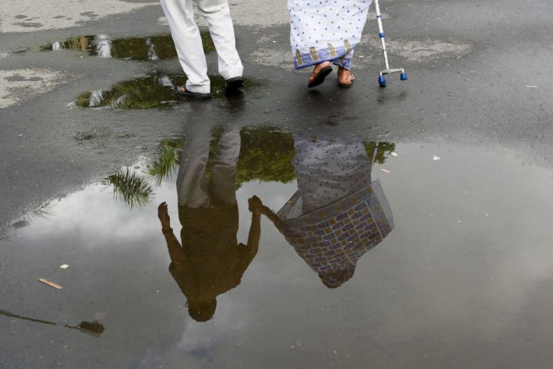 retired-couple An elderly couple holds hands while crossing a wet street.