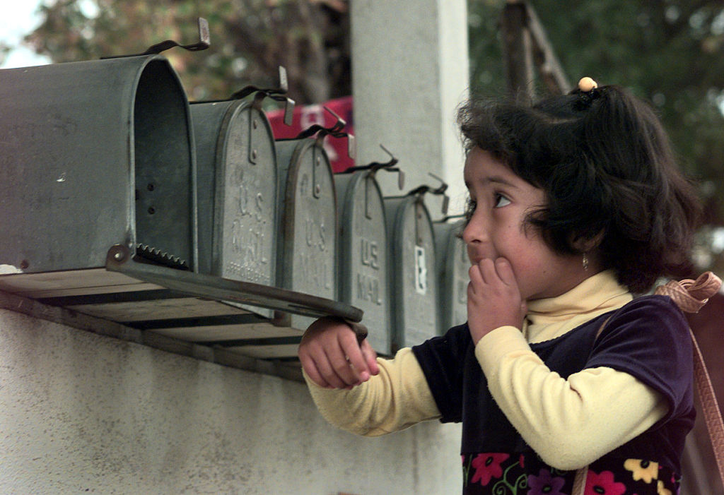 girl-checking-the-mail A young girl checks a mailbox that's one of several identical mailboxes in a row.