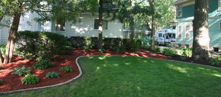 A grassy back yard borders a house.