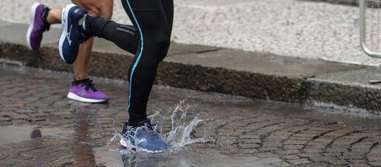 Two people jog through a puddle.