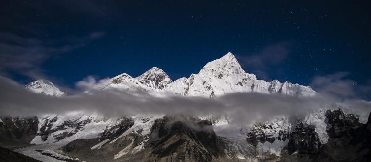 The snowy peak of Mount Everest is seen behind grey clouds.