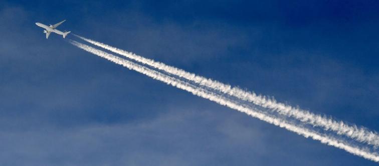 An airplane flies and leaves behind a trail.