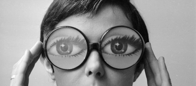 A model wears round glasses with illustrations of eyes on the lenses.