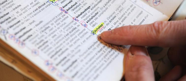 A person points at a French dictionary.