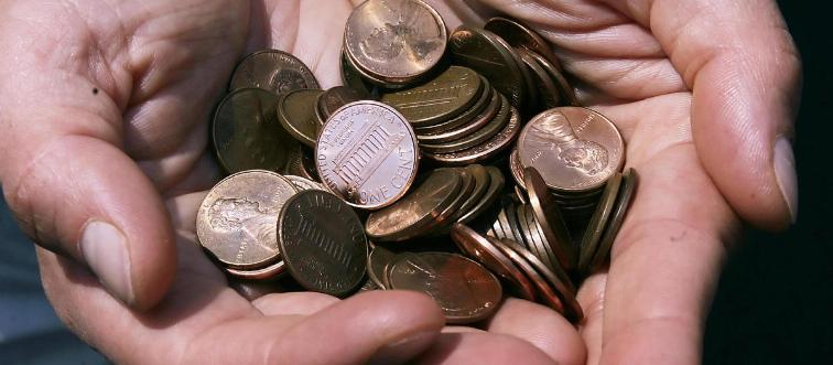 A man holds a pile of pennies.