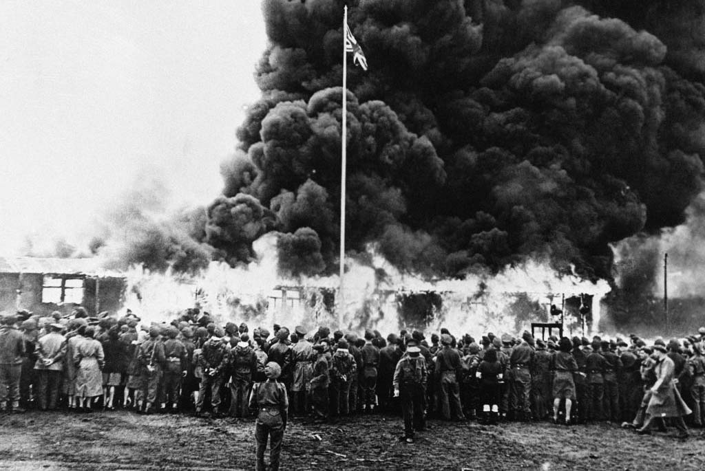 Allied soldiers watching a camp burn 