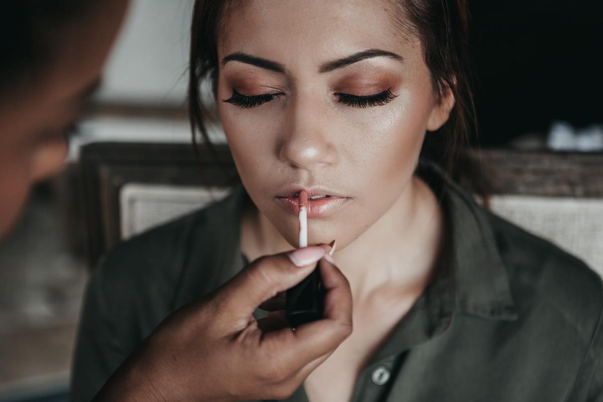 applying makeup A makeup artist applies lip gloss to a customer.