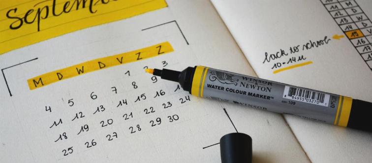 A yellow pen rests on a drawn calendar of September.